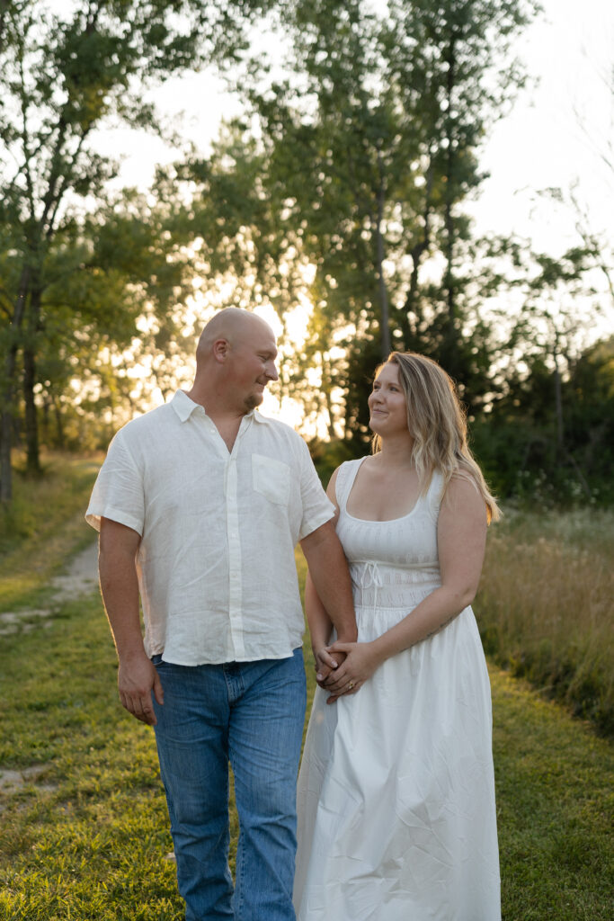 Couple walking, holding hands during an engagement session at Wildcat Bluff Recreation Area in Vinton, IA.