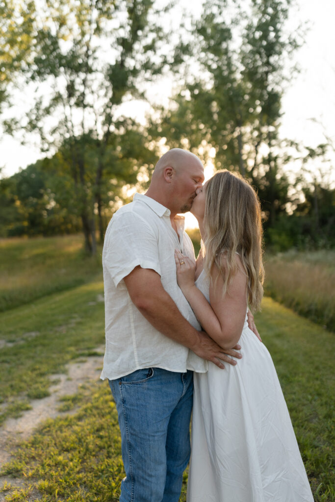 Couple kissing during a golden hour engagement session at Wildcat Bluff Recreation Area in Vinton, IA.