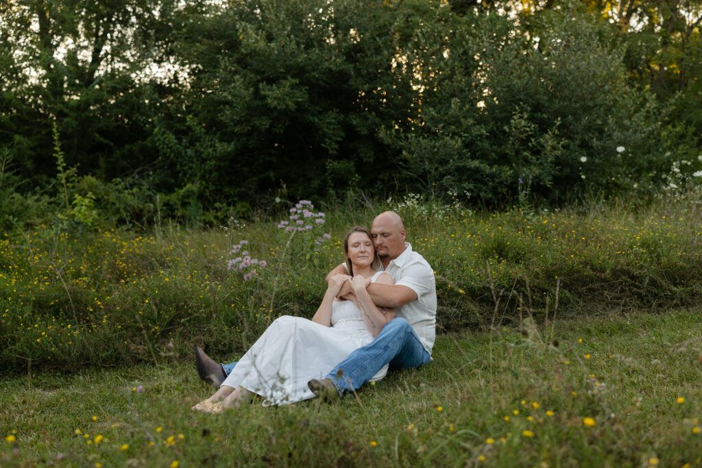 Couple sitting in a field of wild flowers at Wildcat Bluff Recreation Area in Vinton, IA.
