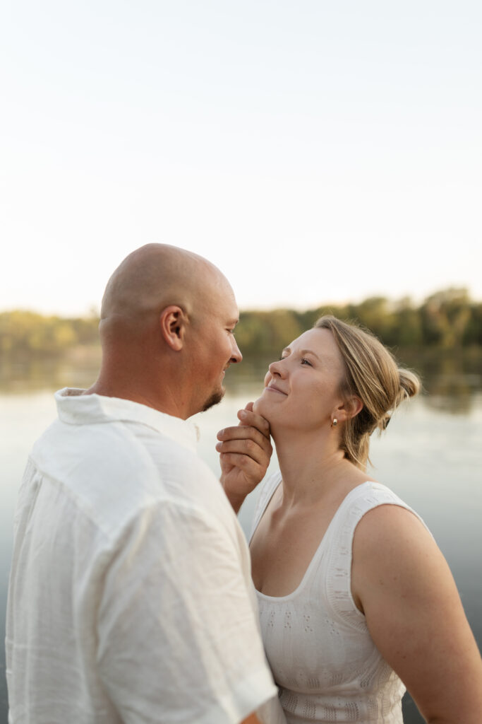 Couple standing in the water as he grabs her chin at Wildcat Bluff Recreation Area in Vinton, IA.