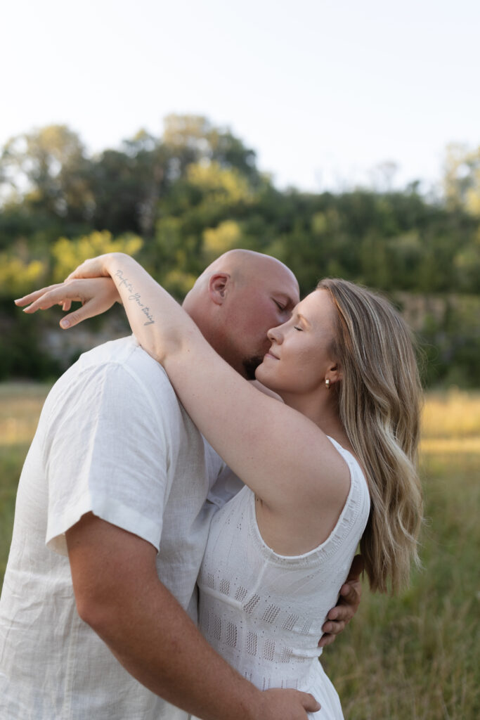 Man kissing woman's cheek during an engagement session at Wildcat Bluff Recreation Area in Vinton, IA.