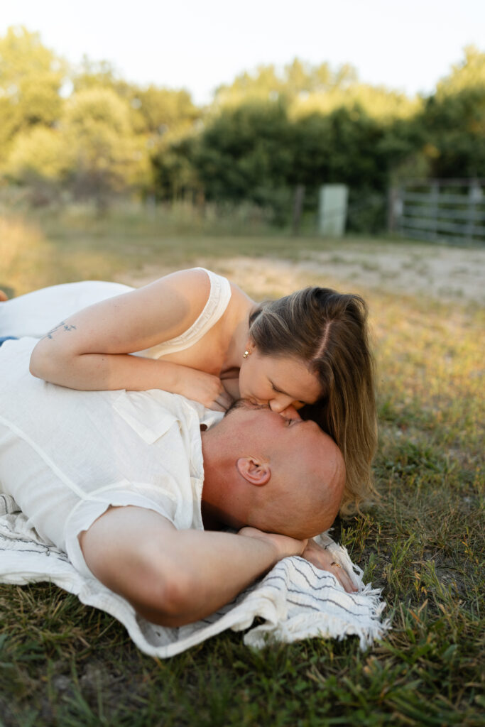 Couple kissing on the ground at Wildcat Bluff Recreation Area in Vinton, IA.